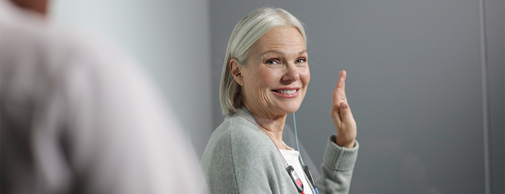 Image of senior woman raising her hand during a hearing test with her hearing care professional